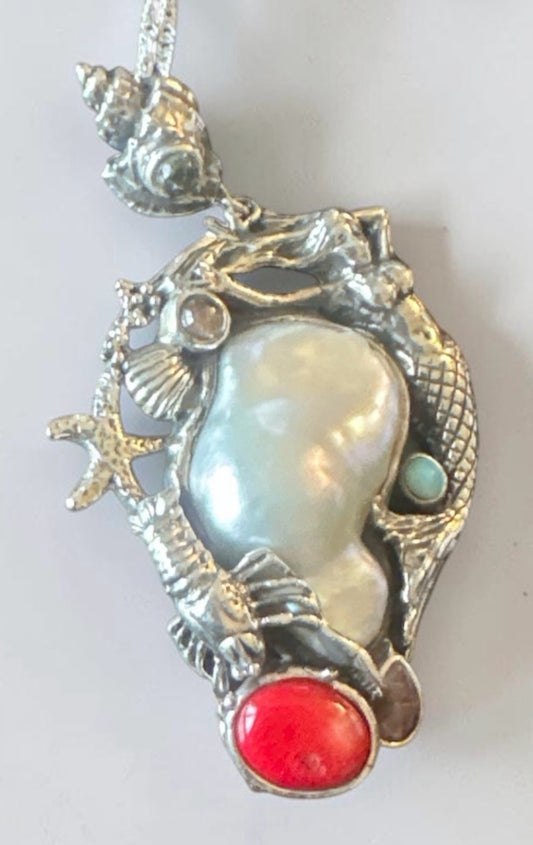 Collana Cristal Milano con pendente a tema marino in metallo argentato, perla barocca, corallo rosso e conchiglie.